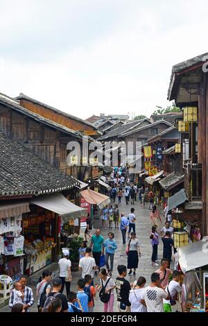 Viele Besucher gehen entlang einer Straße mit Geschäften in der alten Stadt Qingyan in der Nähe von Guiyang, Guizhou, China Stockfoto