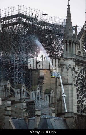 Feuerwehrleute arbeiten, um ein Feuer am Morgen und Sonnenaufgang in der Kathedrale Notre-Dame in Paris am 16. April 2019 zu löschen. Ein gewaltiges Feuer, das die Kathedrale Notre-Dame verwüstet hat, ist "unter Kontrolle", sagte die Pariser Feuerwehr Anfang April 16, nachdem die Feuerwehrleute stundenlang gegen die Flammen gekämpft hatten. Foto von Raphael Lafargue/ABACAPRESS.COM Stockfoto