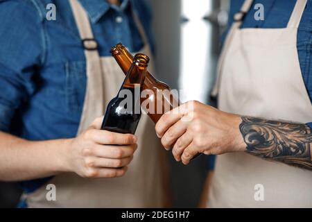 Männlicher Brauereiarbeiter, der Bier probiert und im Betrieb steht Stockfoto