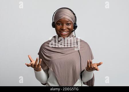 Telemarketin. Schwarze Muslimische Frau In Hijab Trägt Headset Und Spricht Bei Der Kamera Stockfoto