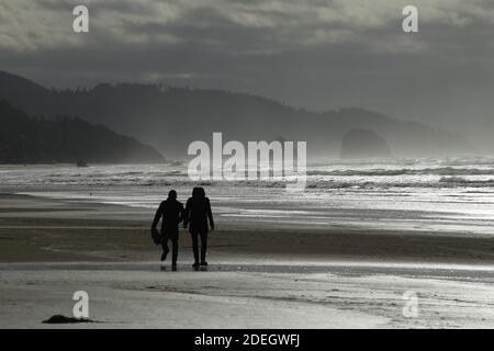 Ein Paar zu Fuß am Ufer des Cannon Beach in Oregon. Stockfoto