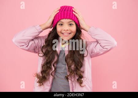 Happy girl Kind Lächeln mit Schönheit Look und lange Brünette Haar Fixierung Mode Mütze Hut auf Kopf rosa Hintergrund, Herbst. Stockfoto