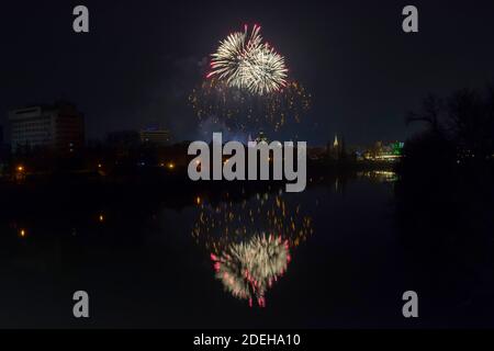 Neujahrsfeier buntes Feuerwerk funkelt in Mitternachtshimmel über der Stadt Arad und Mures Fluss, Rumänien Stockfoto