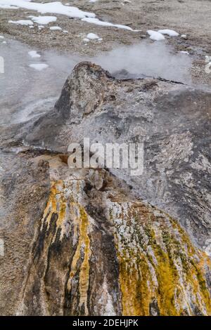 Heißes Wasser aus der heißen Quelle des Schornsteinkegel fließt über Bunte thermophile Mikrobenmatten auf dem Weg ins Feuerloch Fluss im Yellowstone National Stockfoto