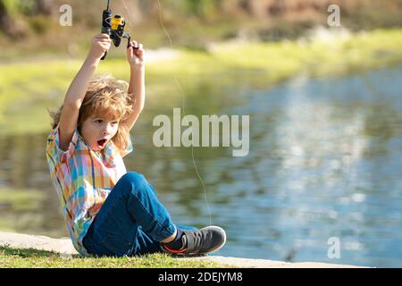 Ein Fischerkind steht mit einer Angelrute im Fluss und fängt Fische. Stockfoto