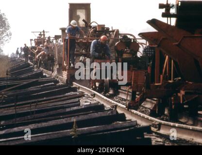 Southern Railway Right-of-Way-Arbeit Crew; mit Maschinen verwendet, um alte Gleise für neue Viertel Meile langen Abschnitte der Schiene zu tauschen. Beachten Sie die neuen Stapel von Eisenbahnschwellen im linken Vordergrund. Ca. 1974 Stockfoto