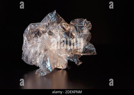 Ein Stück zerknittertes Polyethylen auf schwarzem Hintergrund. Anorganischer Abfall. Konzept Ökologie und Abfallrecycling. Stockfoto