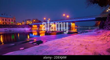 uzhhorod, ukraine - 26 DEC, 2016: Altstadt in einer weihnachtsnacht. Schöne Stadtlandschaft am Fluss. Schnee am Ufer. Brücke und Laternen glühen Stockfoto