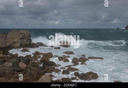 Raue Meere mit Wellen Breaking on the Rocks mit einem Stormy Sky Hintergrund an der Küste der Insel Bryher auf den Inseln von Scilly in England Stockfoto