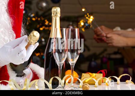 Mann im weihnachtsmann Kostüm öffnet eine Flasche Champagner Stockfoto