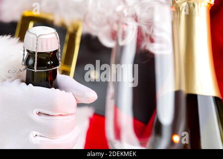 Mann im weihnachtsmann Kostüm öffnet eine Flasche Champagner Stockfoto