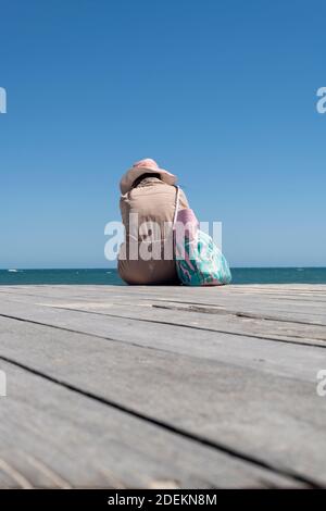 Frau, die allein auf der Promenade von Bathers Beach, Fremantle sitzt. Stockfoto