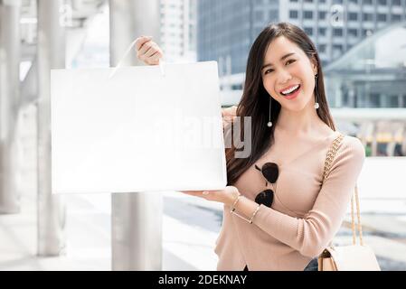 Schöne junge asiatische Frau zeigt ihre Einkaufstasche genießen sie Zeit in der Stadt während der Weihnachtszeit Stockfoto