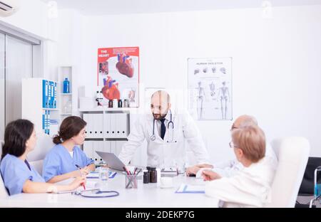 Junge Fachärztin diskutiert mit Kollegen im Klinikkonferenzraum über die Patientendiagnose. Klinik Experte Therapeut im Gespräch mit Kollegen über Krankheit, medizinische Fachkraft Stockfoto
