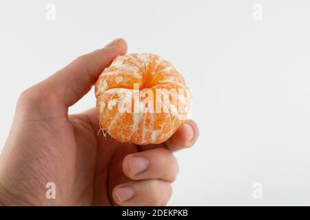 Eine geschälte Mandarine in der Hand auf weißem Hintergrund Stockfoto