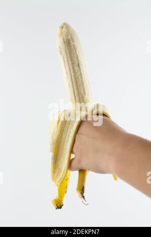 Eine reife geschälte Banane in der Hand auf weißem Hintergrund Stockfoto