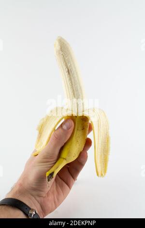 Eine reife geschälte Banane in der Hand auf weißem Hintergrund Stockfoto