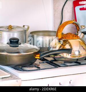 Töpfe, Pfannen und einen Wasserkocher auf dem Gasherd. Gerichte in der Küche Stockfoto