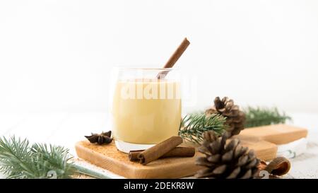 Hausgemachte traditionelle Weihnachten Eierwein trinken in einem Glas mit gemahlener Muskatnuss, Zimt und Dekoration Artikel auf weißem Holztisch, Vorbereitung für Zelebatin Stockfoto