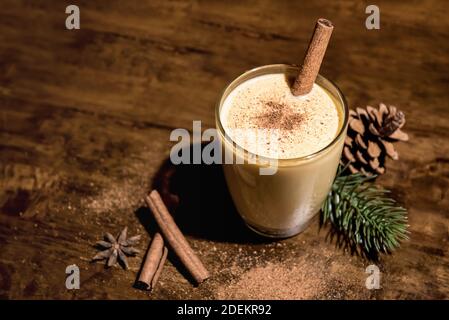 Hausgemachtes traditionelles Weihnachten Eierteller trinken in einem Glas mit gemahlener Muskatnuss, Zimt und Dekoration Artikel auf Holztisch, Vorbereitung für die Feier fest Stockfoto