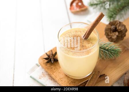 Hausgemachte traditionelle Weihnachten Eierwein trinken in einem Glas mit gemahlener Muskatnuss, Zimt und Dekoration Artikel auf weißem Holztisch, Vorbereitung für Zelebatin Stockfoto