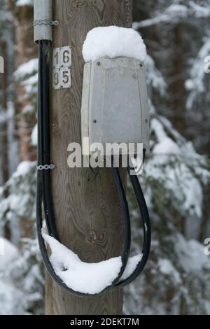 Eine vertikale Aufnahme von elektrischen Meter auf dem Mast während Winter Stockfoto
