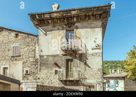 Stadtbild mit einfachen schmiedeeisernen Geländern von Balkonen, die ihren Schatten auf das alte Haus in der historischen Stadt auf dem Hügel werfen, in hellem Licht in Scanno erschossen, Stockfoto