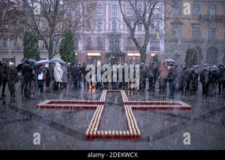 Non Exclusive: LVIV, UKRAINE - 28. NOVEMBER 2020 - die Menschen stehen vor einem Kreuz aus Mahnlaternen, während sie den Opfern der 1932-1 Tribut zollen Stockfoto