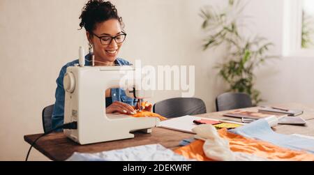 Frau Nähen Gesichtsmaske zu Hause. Frau, die die Nähmaschine verwendet, um die schützende Gesichtsmaske zu nähen. Stockfoto