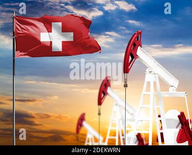 Ölbohrinseln vor dem Hintergrund des bunten Himmels und einer Fahnenstange mit der Flagge der Schweiz. Das Konzept der Ölproduktion, Mineralien, Entwicklung von Stockfoto