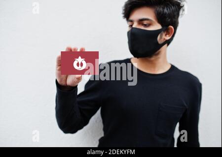 Japanischer Mann tragen ganz schwarz mit Gesichtsmaske halten Aichi Flagge in der Hand isoliert auf weißem Hintergrund. Präfekturen von Japan сoronavirus Konzept. Stockfoto