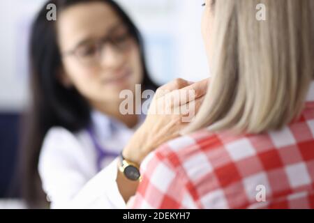 Arzt berührt Patienten submandibuläre Lymphknoten mit den Händen in Klinik Stockfoto