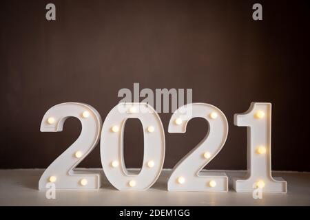 Abbildungen 2021 mit Lichtern auf braunem Hintergrund. Frohe Weihnachten und ein glückliches neues Jahr Stockfoto