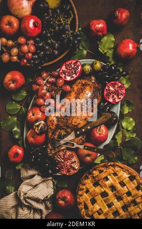 Herbst Thanksgiving, Friendsgiving, Familienessen. Flacher Herbsttisch mit gebratener Ente in saisonalen Früchten und Apfelkuchen mit Kürbissen und Blättern auf rostigen Hintergrund Stockfoto