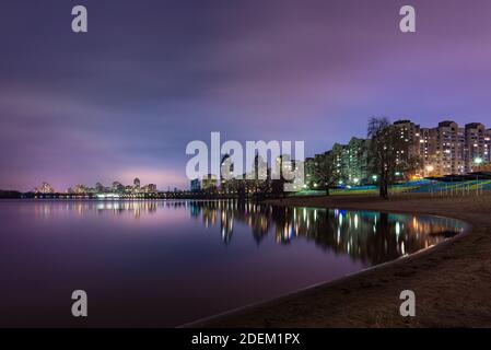Nachtansicht der modernen Gebäude in der Obolon Bezirk von Kiew, Ukraine, in der Nähe des Flusses Dnjepr, die Lichter reflektieren auf dem ruhigen Wasser. Stockfoto