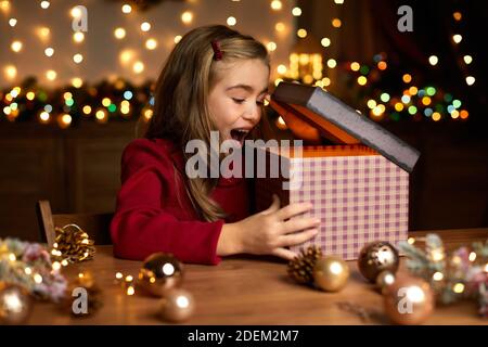 Schöne überrascht kleines Kind Mädchen Eröffnung magische Weihnachten Geschenkbox zu Hause. Weihnachtswunder Stockfoto