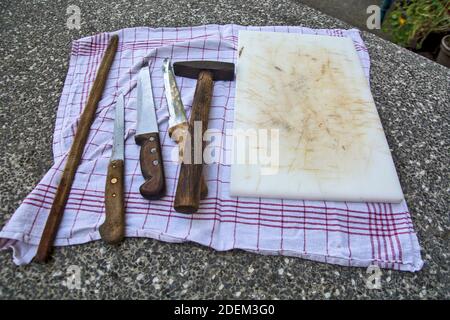 Drei Messer, ein Brett zum Schneiden von Fleisch und ein Hammer auf einem Betontisch. Warten, um das Fleisch zu schneiden zu bringen. Stockfoto