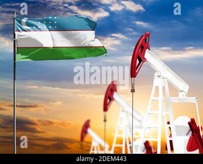 Ölbohrinseln vor dem Hintergrund des bunten Himmels und einer Fahnenstange mit der Flagge Usbekistans. Das Konzept der Ölproduktion, Mineralien, Entwicklung von Stockfoto