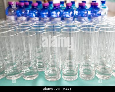 Selektiver Fokus auf leere saubere transparente Gläser. Es gibt eine Menge Flaschen mit Getränken auf einem unscharfen Hintergrund. Catering. Bankett. Stockfoto