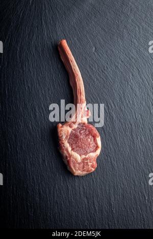 Scheiben rohe Lammkoteletts auf schwarzem Tisch. Draufsicht. Stockfoto