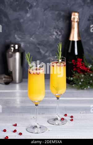 Mimosa Cocktail mit Orangensaft und Champagner. Neujahrs- oder Geburtstagsfeier. Granatapfel und Rosmarin Stockfoto