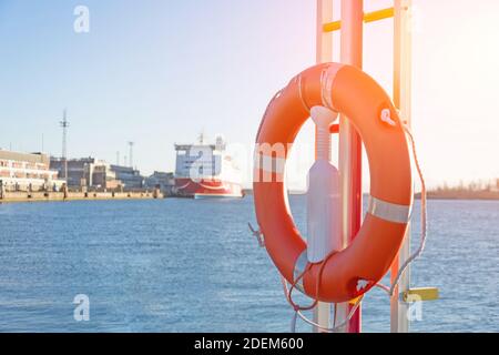 Rettungsring am Pier im Hafen, im Hintergrund ein Passagierschiff in der Bucht Stockfoto