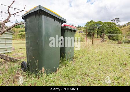 Ein Hausmüll- und Recyclingbehälter sitzt an einem Zaun auf einem grasbewachsenen Rand außerhalb einer Farm in New South Wales, Australien Stockfoto