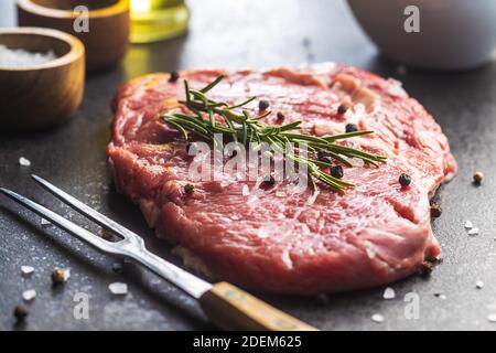 Geschnittenes rohes Ribeye Steak auf einem schwarzen Küchentisch. Stockfoto