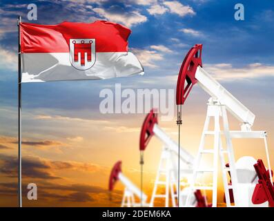 Ölbohrinseln vor der Kulisse des bunten Himmels und einer Fahnenstange mit der Flagge Vorarlbergs. Das Konzept der Ölproduktion, Mineralien, Entwicklung von Stockfoto