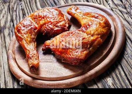 Hähnchenschenkelvierteln, im Ofen gebacken, hautnah, Knochen-in, serviert auf einem hölzernen Hintergrund, Draufsicht, Nahaufnahme Stockfoto