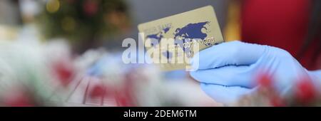 Hand in Handschuh hält eine Plastikkarte vor dem Hintergrund Der Neujahrsdekoration Stockfoto
