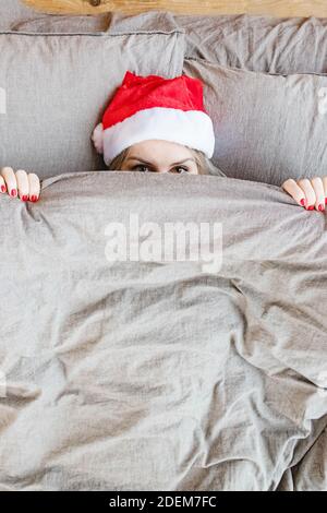 Frau im Bett tragen weihnachtsmann roten Hut über ihr Gesicht Mit blanke Stockfoto