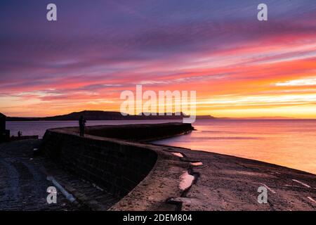 Lyme Regis, Dorset, Großbritannien. Dezember 2020. UK Wetter: Spektakuläre Sonnenaufgangsfarben über historischen Cobb, Lyme Regis.. Kredit: Celia McMahon/Alamy Live Nachrichten Stockfoto