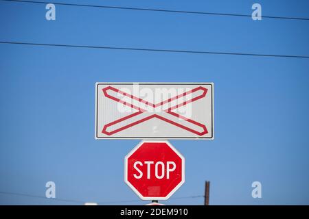 Bahnübergangsschild, genannt Crossbuck, Saltire oder Saint Andrews Kreuz, steht auf einer Straße, die eine Eisenbahnstrecke in Pancevo, Serbien, mit einem sta kreuzt Stockfoto